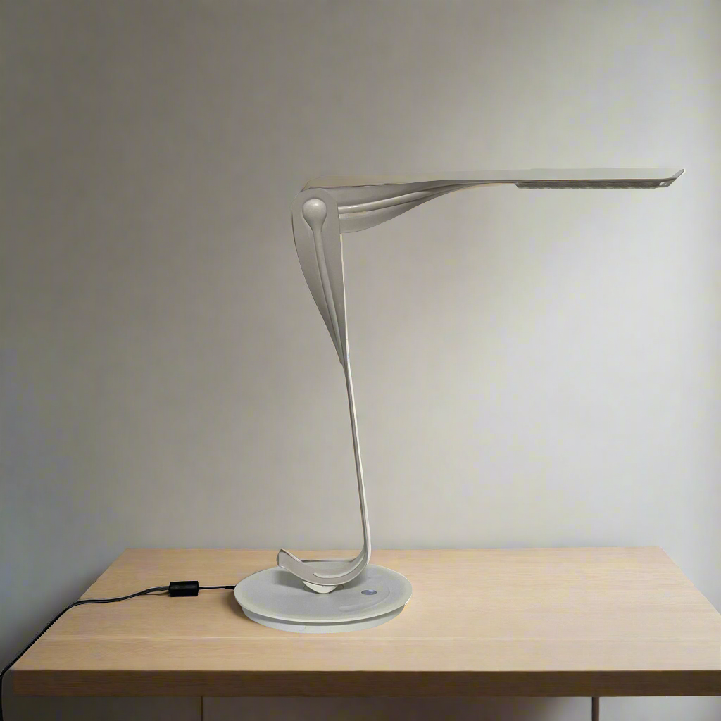 A sleek, modern Herman Miller Leaf Task Light with a curved design on a circular base, connected to a power cord.