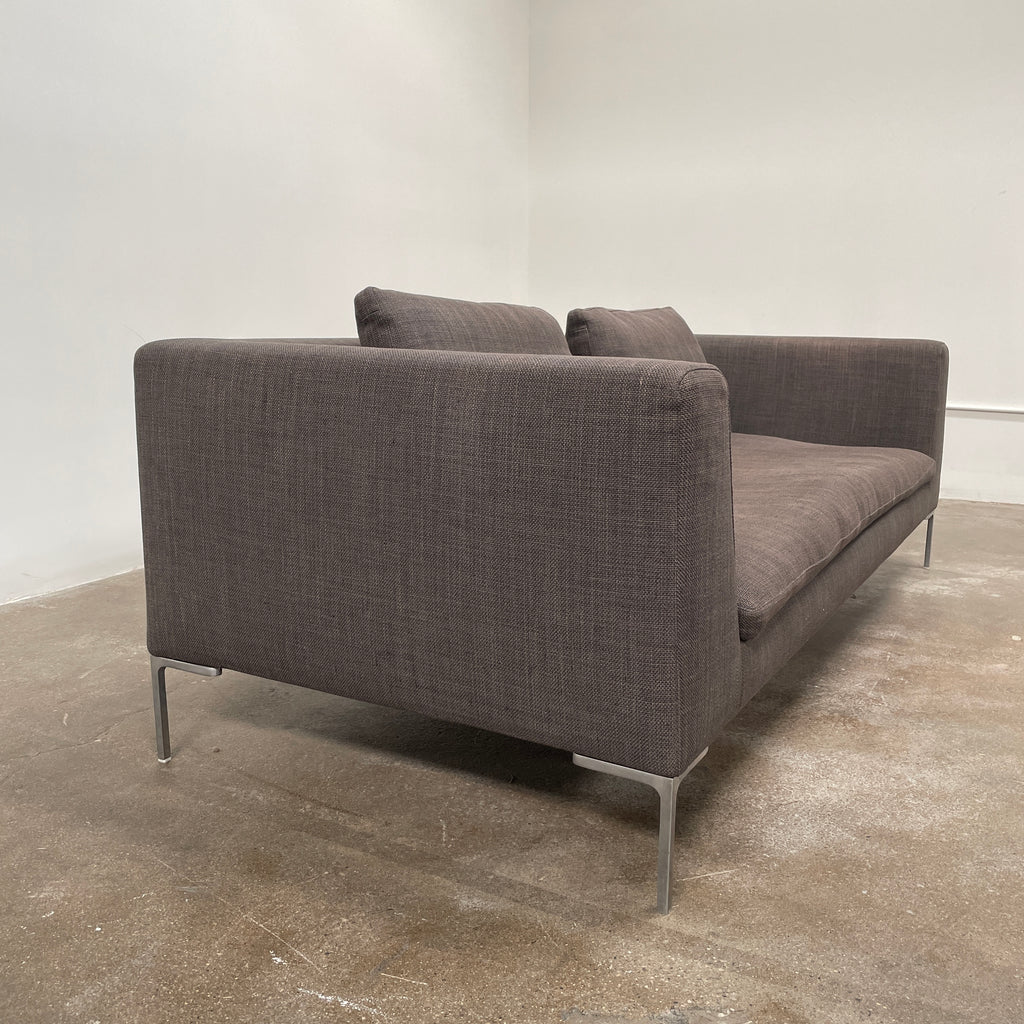 The luxurious B&B Italia Charles Sofa by B&B Italia, a modern brown piece with two seat cushions and two back cushions, boasts straight armrests and thin metal legs. It is elegantly placed against a plain white background.