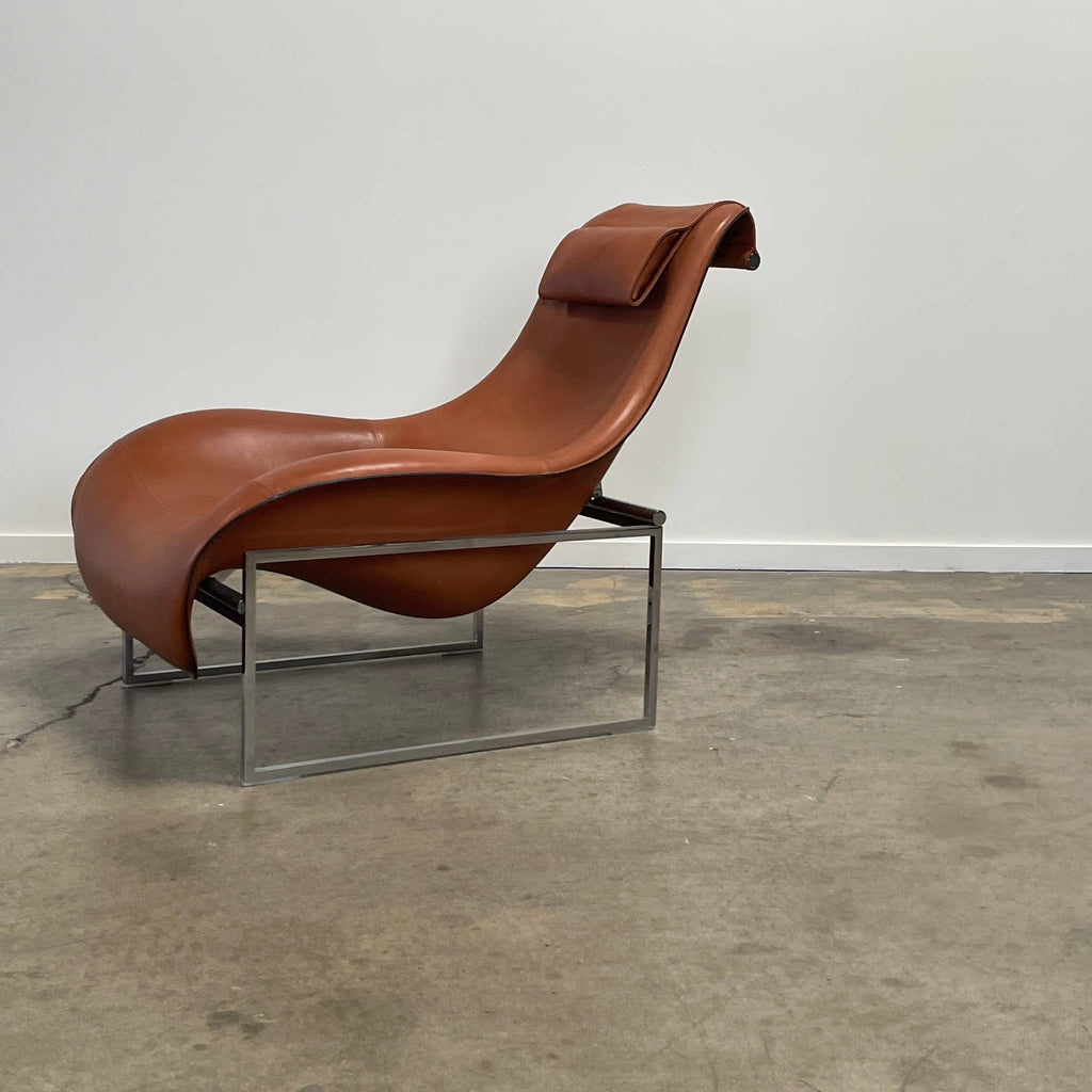 A contemporary brown leather B&B Italia Mart Reclining Armchair, featuring a headrest, is positioned against a minimal gray wall and concrete floor.