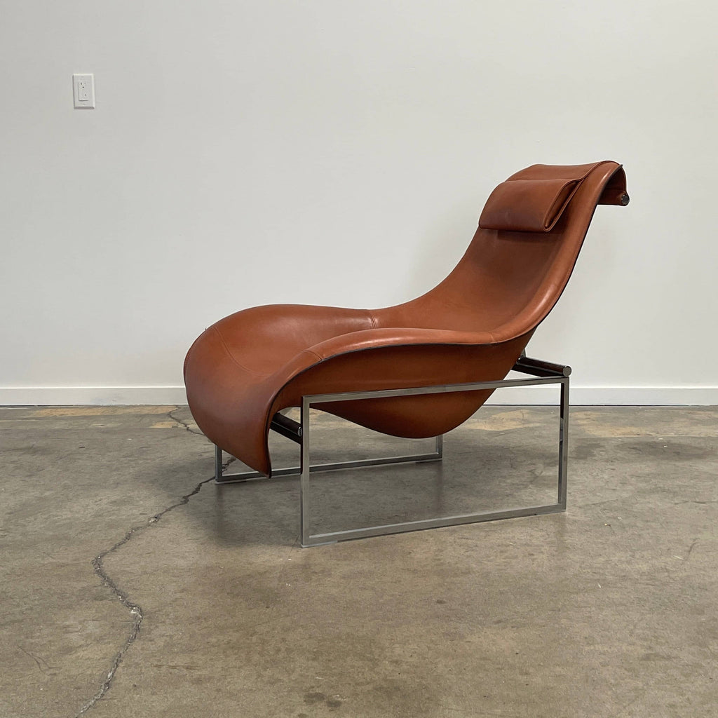 A contemporary brown leather B&B Italia Mart Reclining Armchair, featuring a headrest, is positioned against a minimal gray wall and concrete floor.