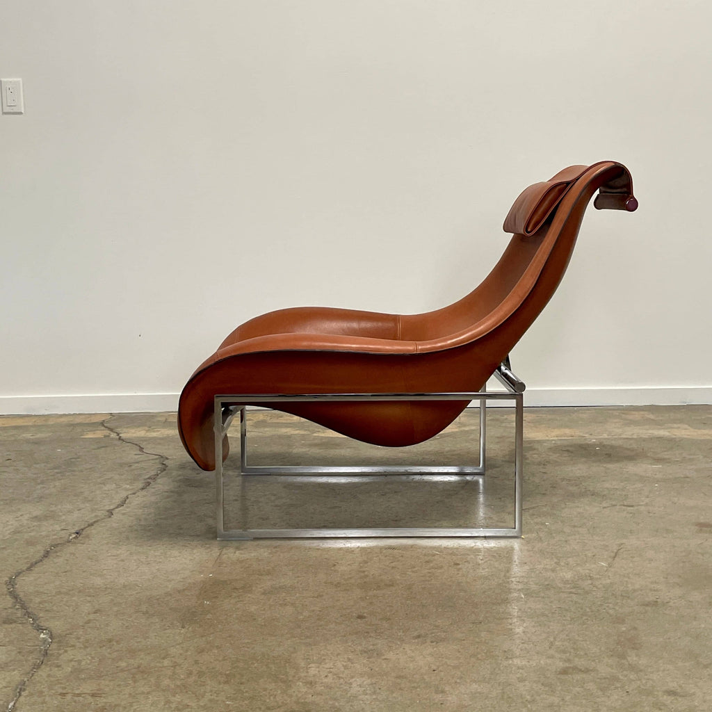 A contemporary brown leather B&B Italia Mart Reclining Armchair, featuring a headrest, is positioned against a minimal gray wall and concrete floor.