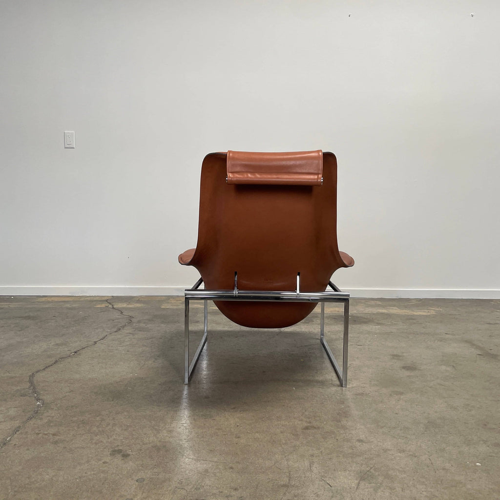 A contemporary brown leather B&B Italia Mart Reclining Armchair, featuring a headrest, is positioned against a minimal gray wall and concrete floor.