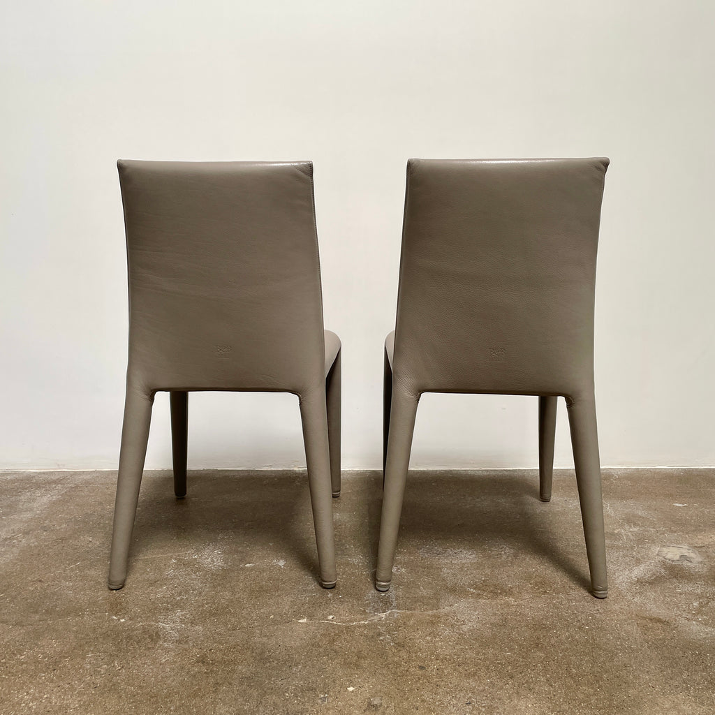 Six B&B Italia Vol au Vent Dining Chairs, embodying the elegance of Italian style, are arranged in two rows in an empty room with a concrete floor and a plain white wall.