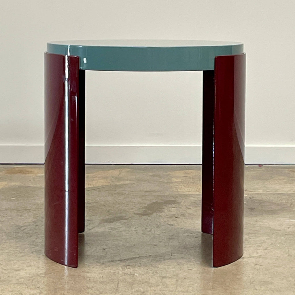 The Cassina Bowy Side Table by Cassina draws from Patricia Urquiola's organic design flair, showcasing a contemporary round structure with a light gray surface and an eye-catching red, curved base.