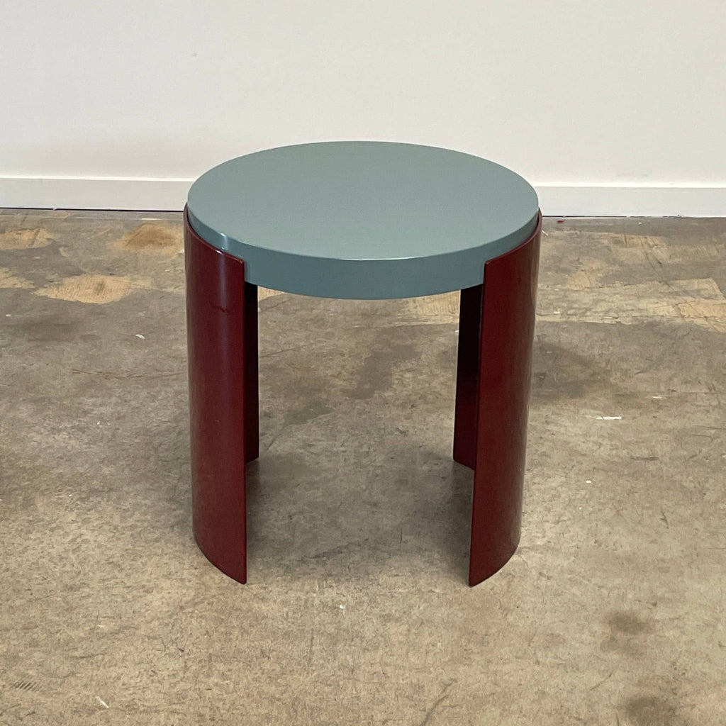 The Cassina Bowy Side Table by Cassina draws from Patricia Urquiola's organic design flair, showcasing a contemporary round structure with a light gray surface and an eye-catching red, curved base.