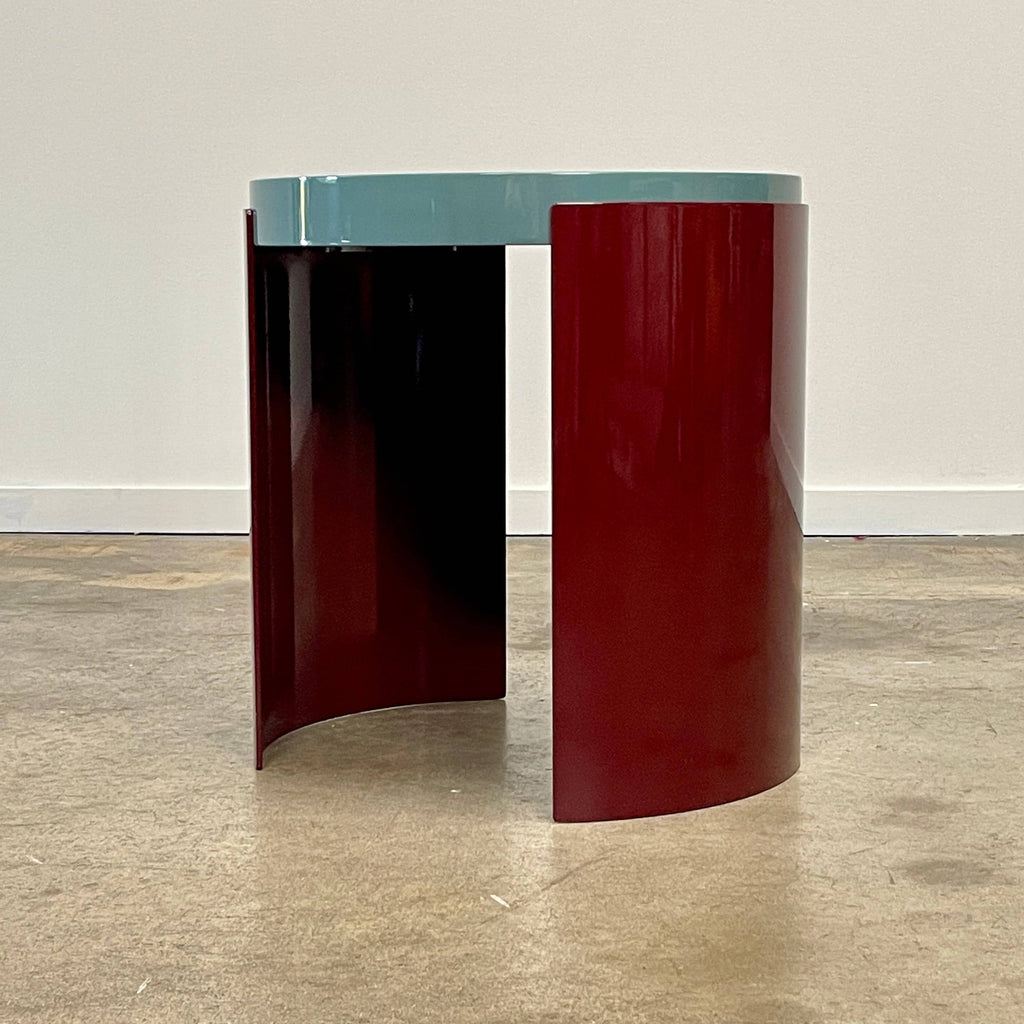 The Cassina Bowy Side Table by Cassina draws from Patricia Urquiola's organic design flair, showcasing a contemporary round structure with a light gray surface and an eye-catching red, curved base.