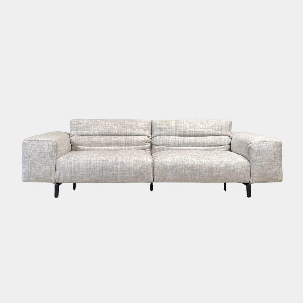 The Cassina 204 Scighera Three Seater Sofa by Cassina, designed by Piero Lissoni, showcases a minimalist design with its modern light gray upholstery and sleek black legs against a plain background.