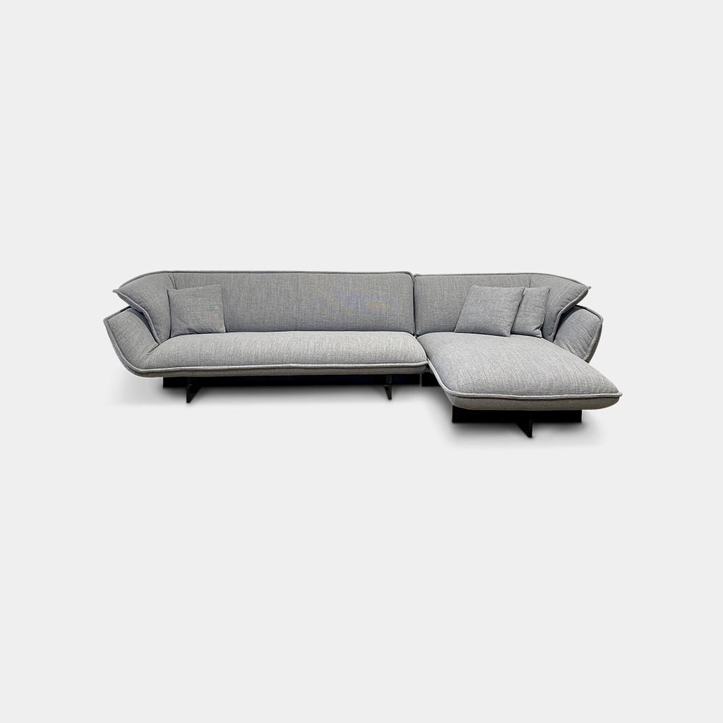 The Cassina Beam Sectional by Cassina, designed by Patricia Urquiola, is a refined gray L-shaped upholstered sectional featuring plush cushions contrasted with a clean white background.