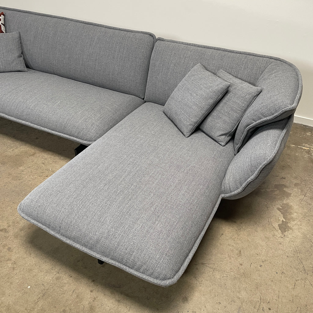 The Cassina Beam Sectional by Cassina, designed by Patricia Urquiola, is a refined gray L-shaped upholstered sectional featuring plush cushions contrasted with a clean white background.