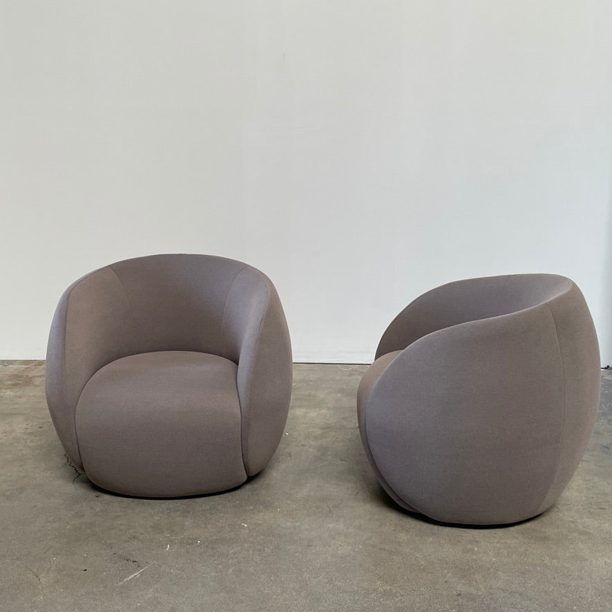 Two Roche Bobois Dot Chairs from the prestigious Roche Bobois brand, featuring a sleek grey and modern curved design, are positioned on a plain, light background. One chair faces forward while the other showcases its side profile, enhancing their sophisticated allure.