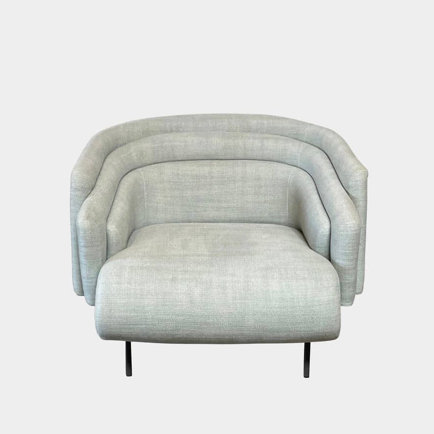 The Delcourt Collection Hug Armchair, upholstered in a delightful light blue fabric, features sleek black legs.