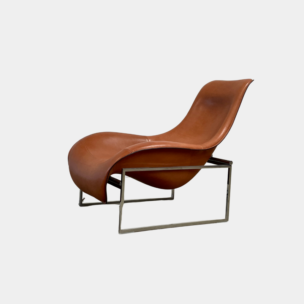 A contemporary brown leather B&B Italia Mart Reclining Armchair, featuring a headrest, is positioned against a minimal gray wall and concrete floor.