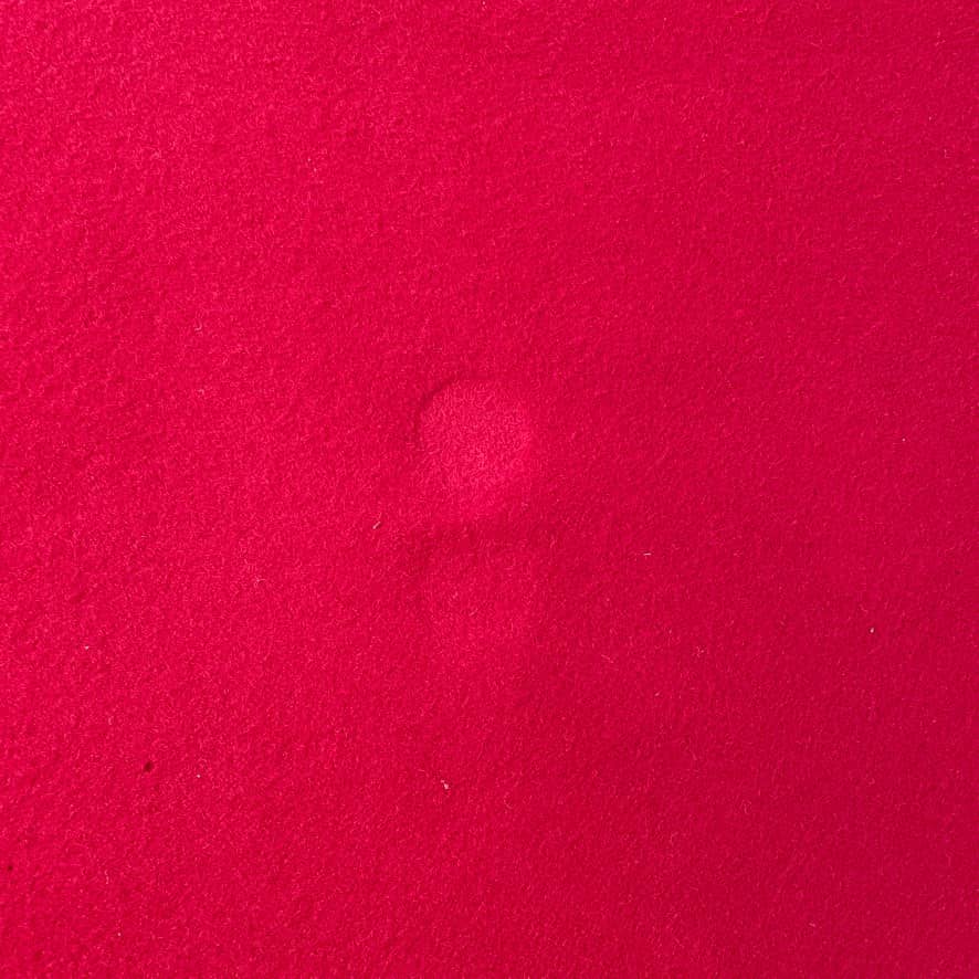 Close-up of the corner of a Large Felt Rug in a vibrant red color against a white background. The fabric showcases a clearly visible seam along its edge.