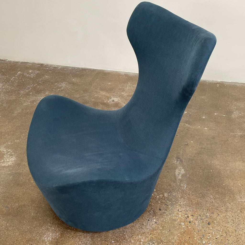 A modern, dark blue B&B Italia Grande Papilio Swivel Chair by Naoto Fukasawa showcases a curved design with a high backrest and wide seat, set against a plain white background.