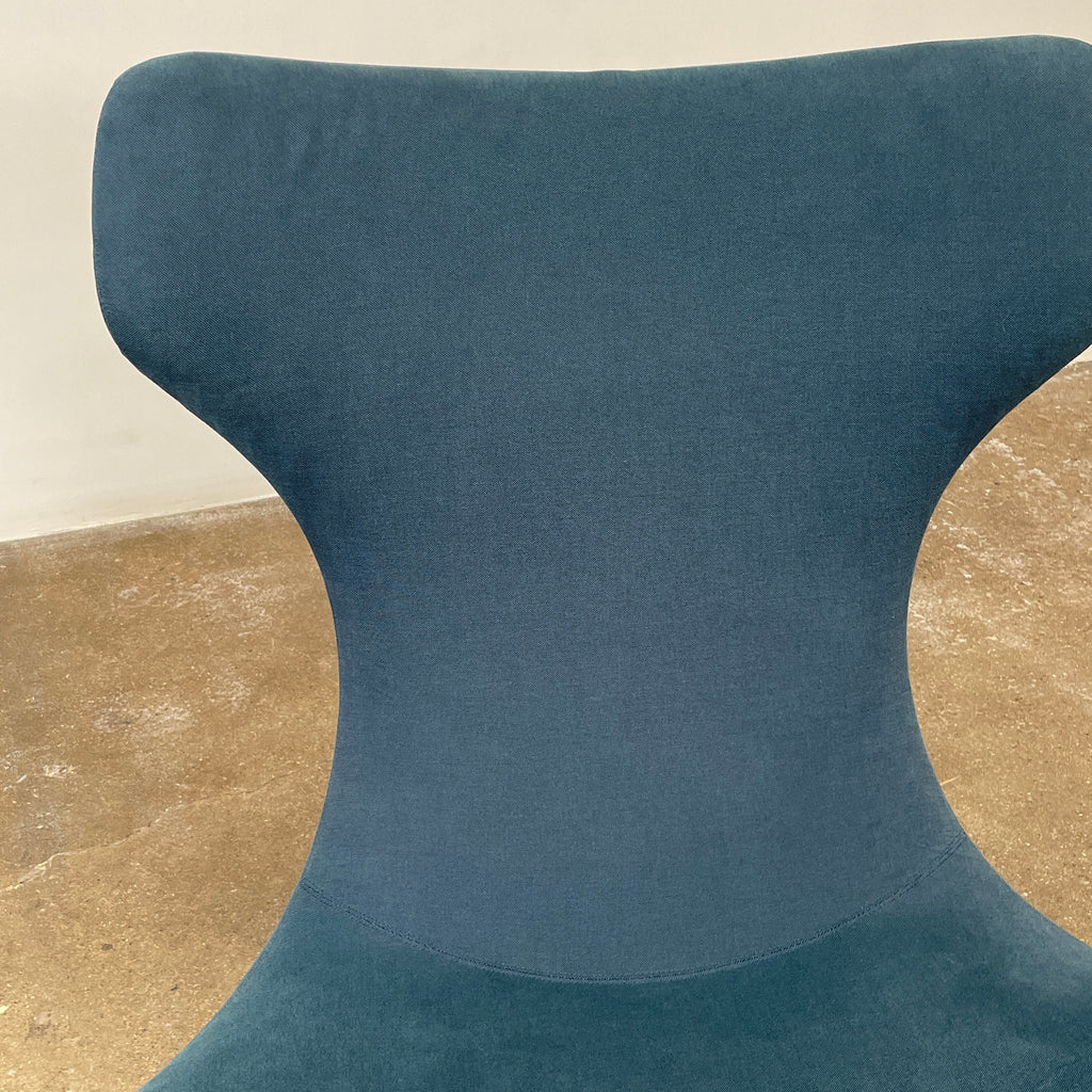 A modern, dark blue B&B Italia Grande Papilio Swivel Chair by Naoto Fukasawa showcases a curved design with a high backrest and wide seat, set against a plain white background.