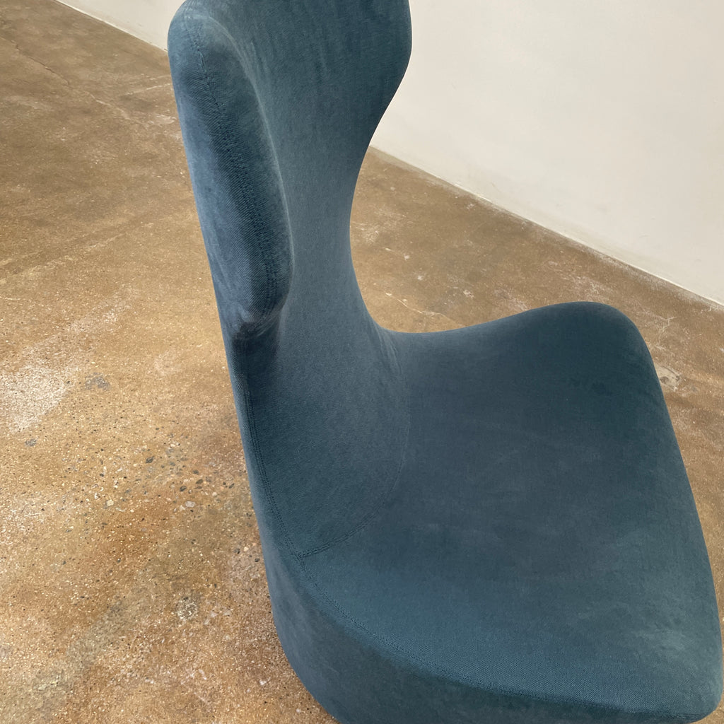 A modern, dark blue B&B Italia Grande Papilio Swivel Chair by Naoto Fukasawa showcases a curved design with a high backrest and wide seat, set against a plain white background.