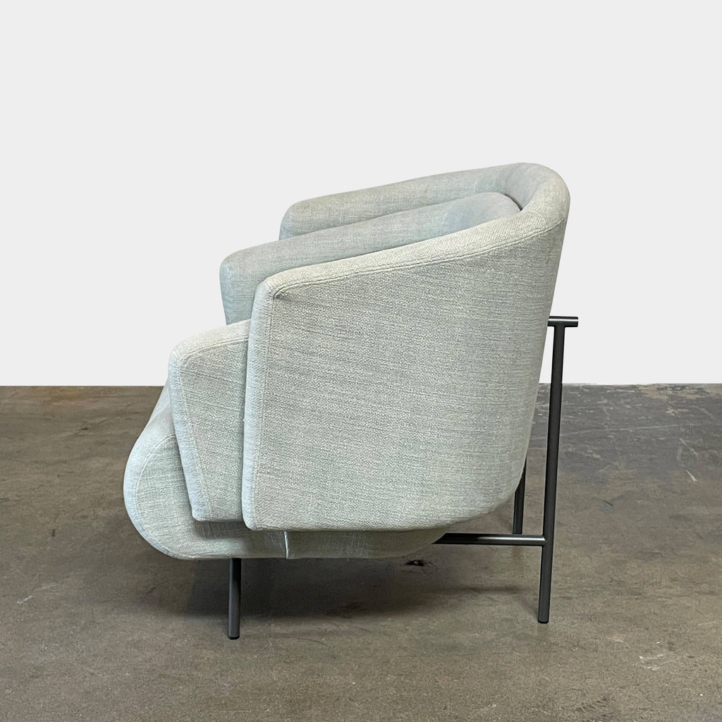 The Delcourt Collection Hug Armchair, upholstered in a delightful light blue fabric, features sleek black legs.