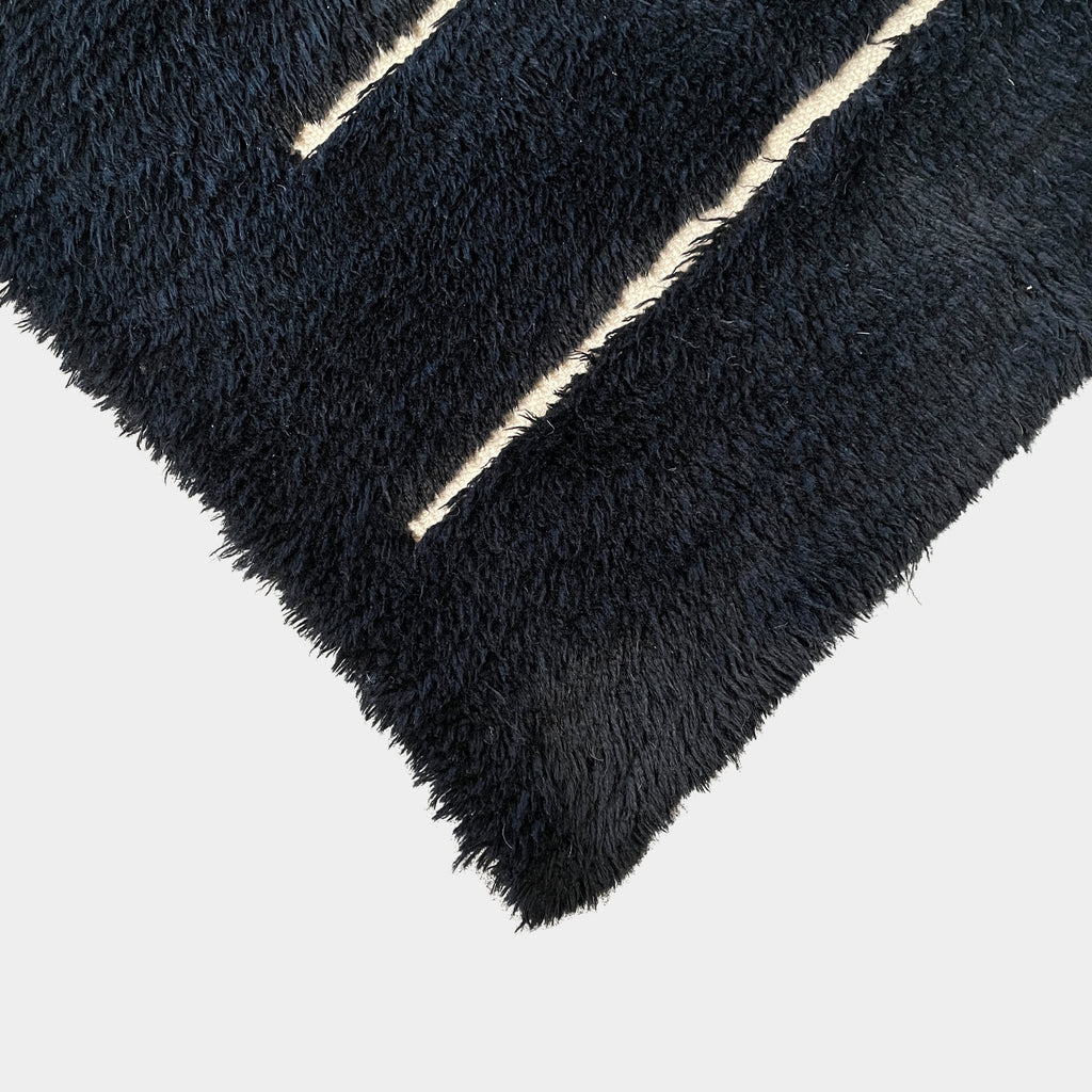 Close-up of a Woven Dilla Black & Ivory wool rug with diagonal white stitching, creating a distinct pattern on a high/low pile surface.