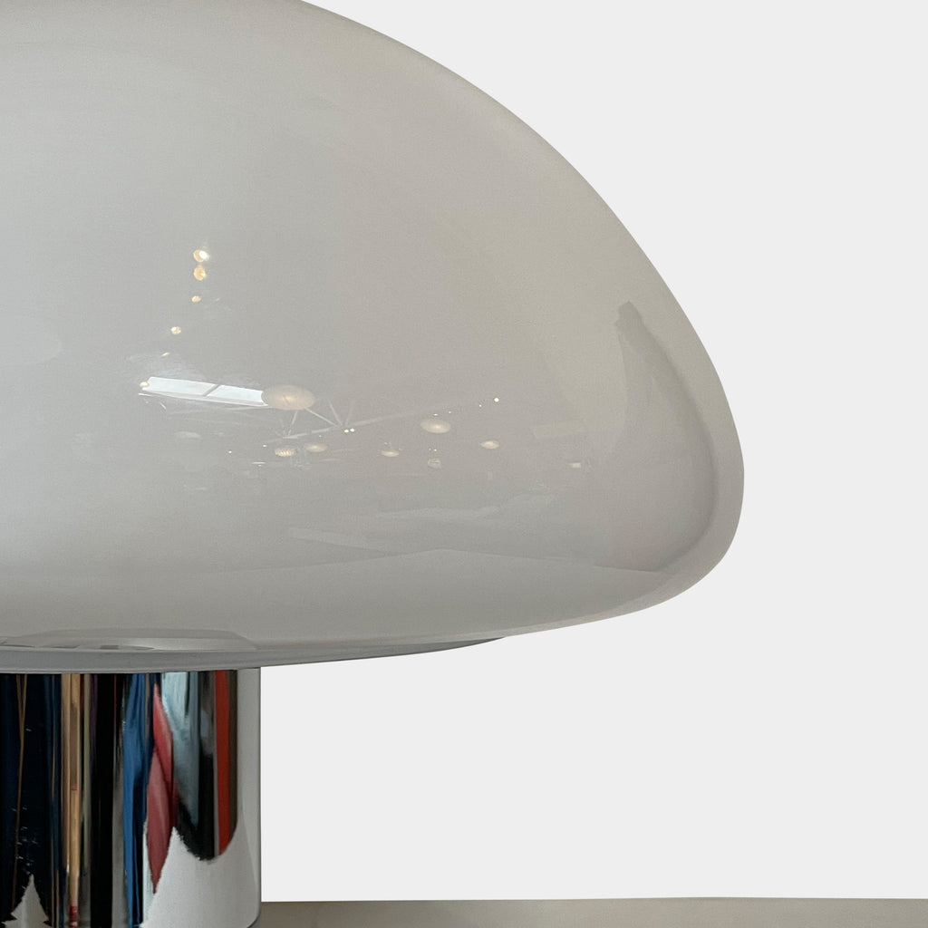 The Nahoor K&W Table Light features a large, dome-shaped beige shade and a cylindrical base crafted with exquisite Murano glass. This elegant piece reflects Italian design and sophistication, complete with a black power cord and switch.