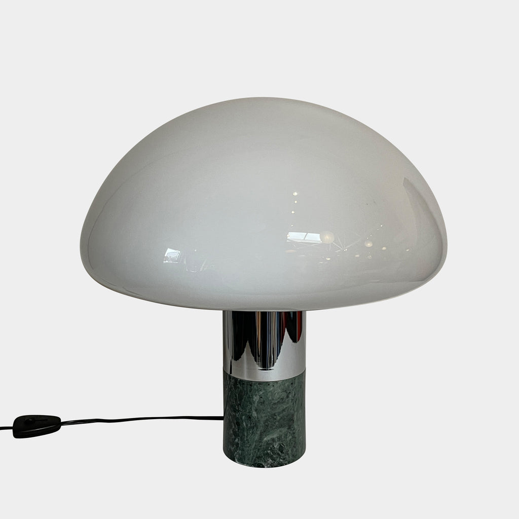 The Nahoor K&W Table Light features a large, dome-shaped beige shade and a cylindrical base crafted with exquisite Murano glass. This elegant piece reflects Italian design and sophistication, complete with a black power cord and switch.