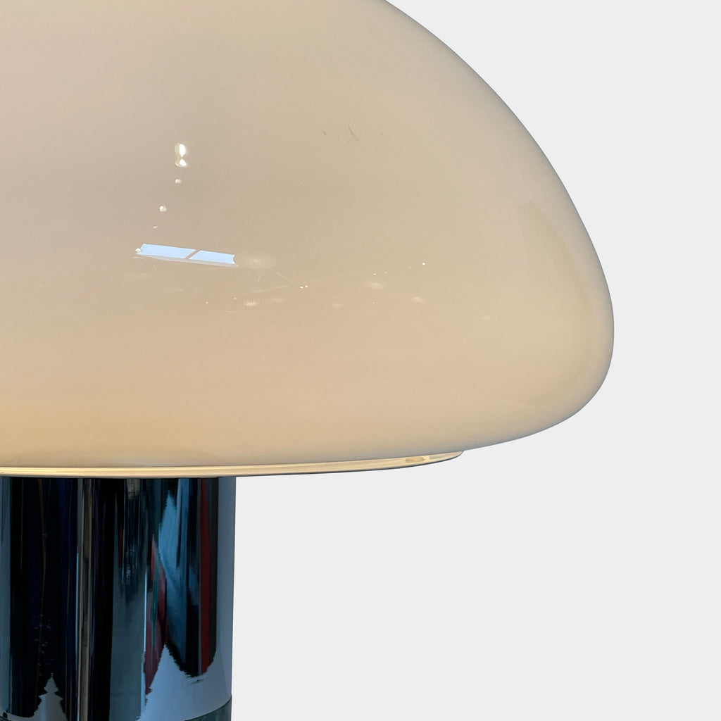 The Nahoor K&W Table Light features a large, dome-shaped beige shade and a cylindrical base crafted with exquisite Murano glass. This elegant piece reflects Italian design and sophistication, complete with a black power cord and switch.