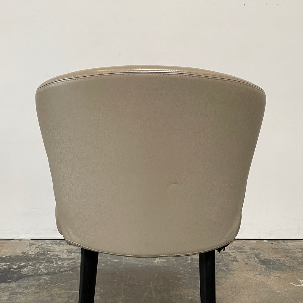 A pair of Minotti Aston Counter Stools, featuring beige cushioned backs and seats supported by sleek black-finished solid ash legs, is displayed against a plain background.