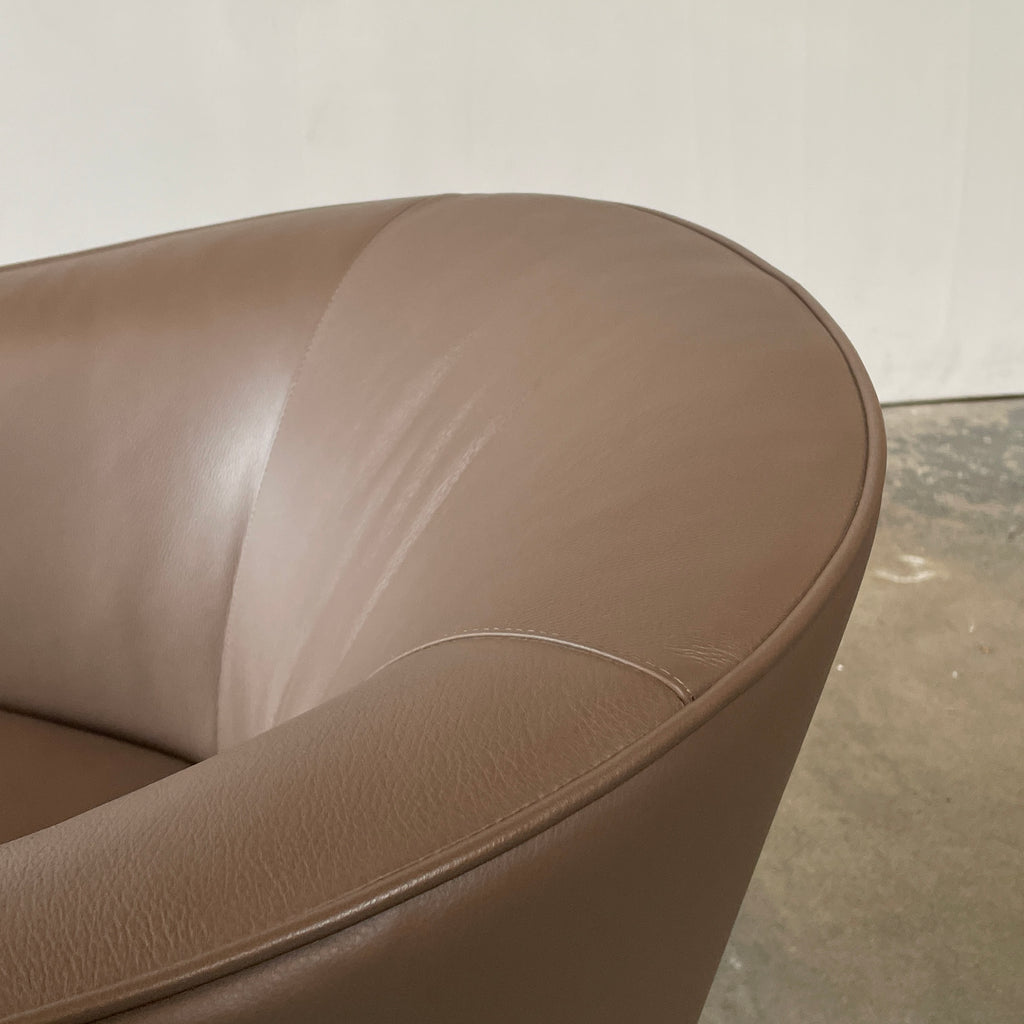 A Minotti Martin Brown Leather Swivel Chair with a cushioned seat and back, sitting on a sleek black chrome base, against a plain white background.