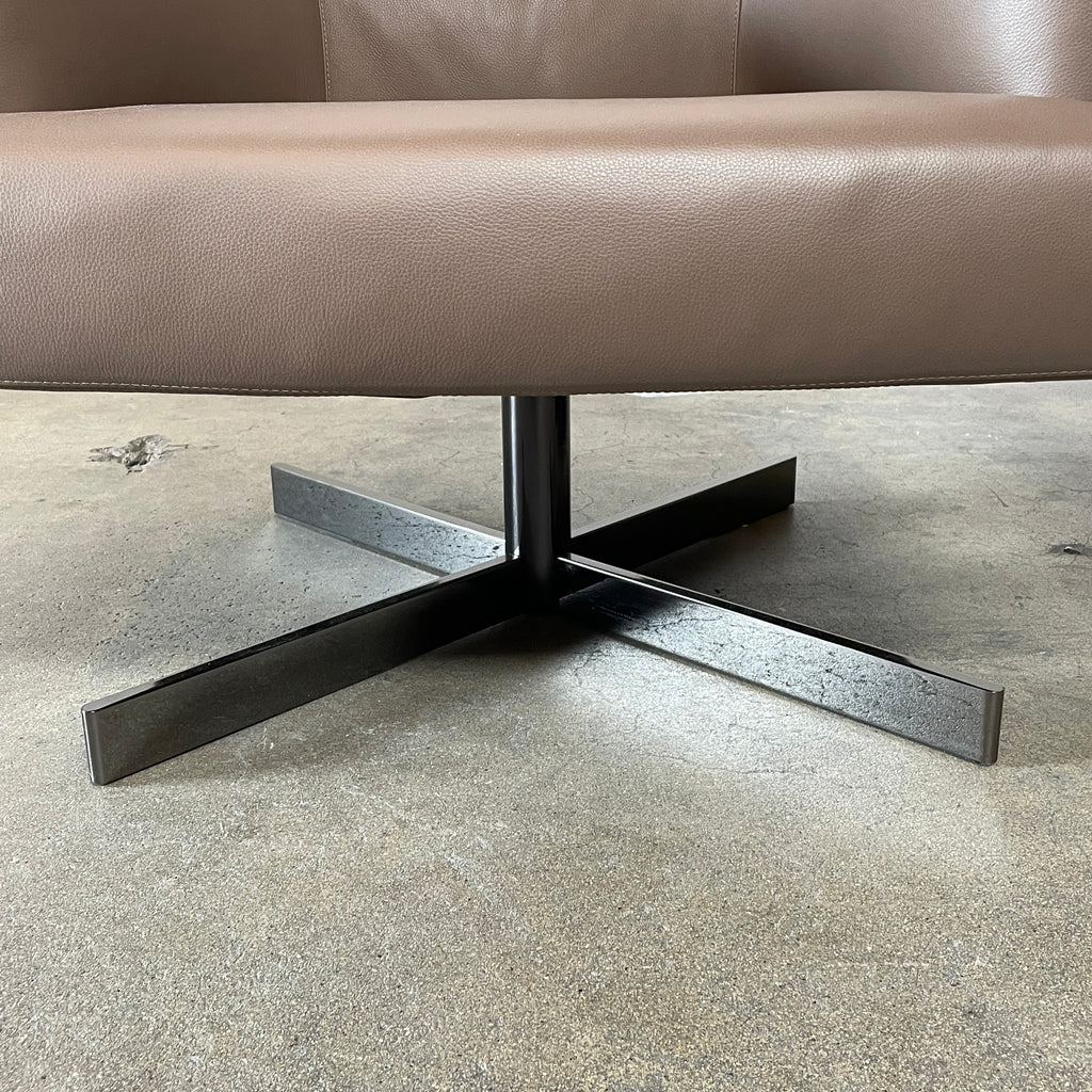 A Minotti Martin Brown Leather Swivel Chair with a cushioned seat and back, sitting on a sleek black chrome base, against a plain white background.