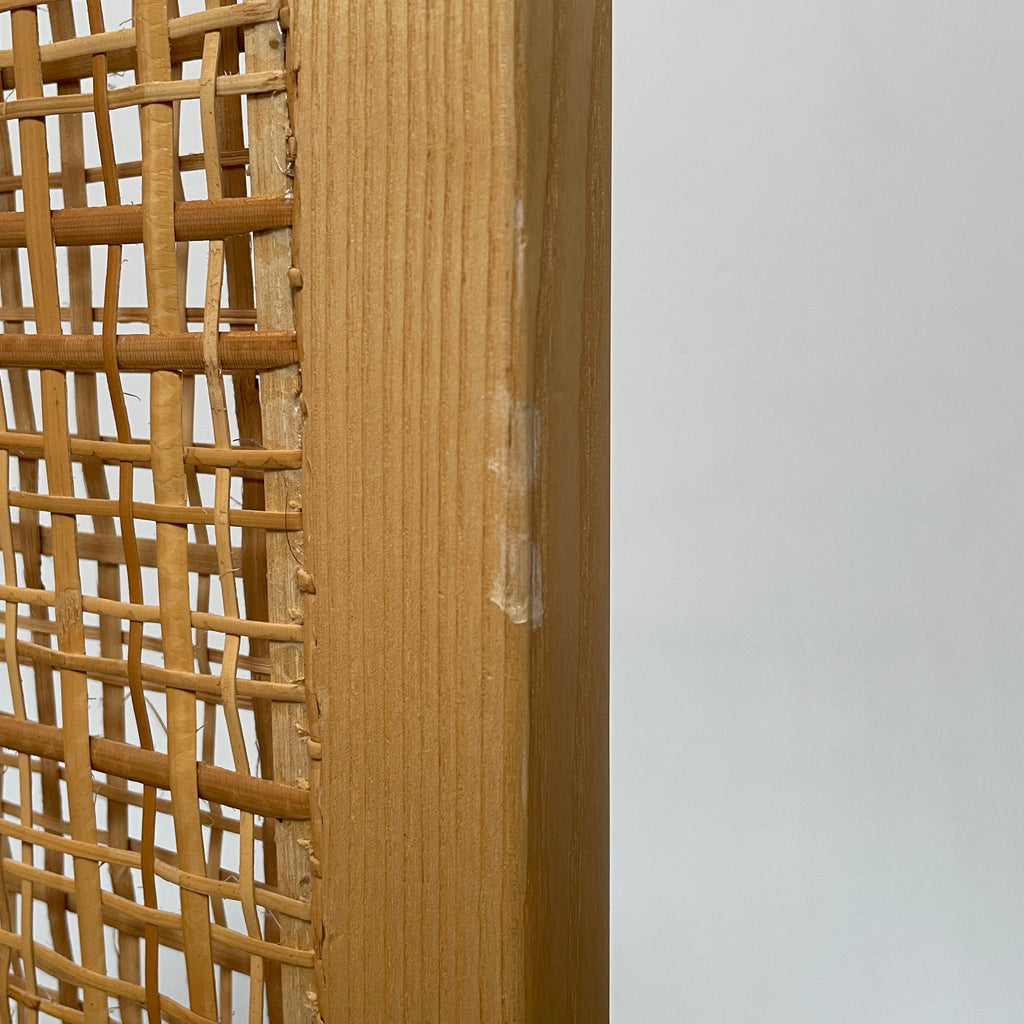 Close-up view of a wooden frame with a woven wicker panel, showcasing Lebanese craftsmanship. The wood shows a small patch of wear, offering a glimpse into the meticulous detailing associated with Nada Debs' contemporary Arabesque designs in the Nada Debs Summerland Folding Screen.