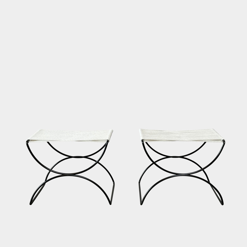 Two TEN10 Pompeii Low Outdoor Stools by TEN10 with mid-century modernist design feature curved black wrought iron bases and white, fabric-covered seats set against a plain white background.