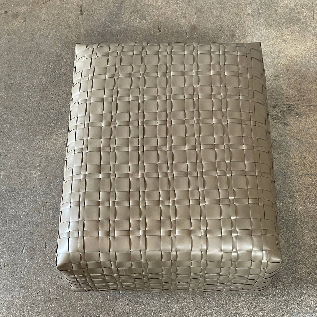 A square, beige Flexform Bangkok Ottoman with a woven leather pattern and four short metal legs evokes the stylish charm of Bangkok.