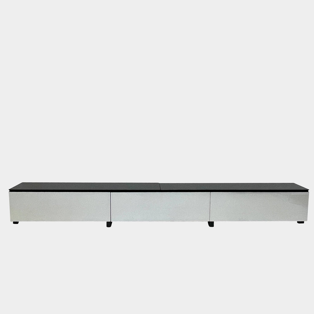 A low, modern white sideboard with a sleek black top and three compartments offers ample storage, set against a plain white background. The B&B Italia Pab Low Console by B&B Italia boasts a glossy finish that enhances its contemporary appeal.