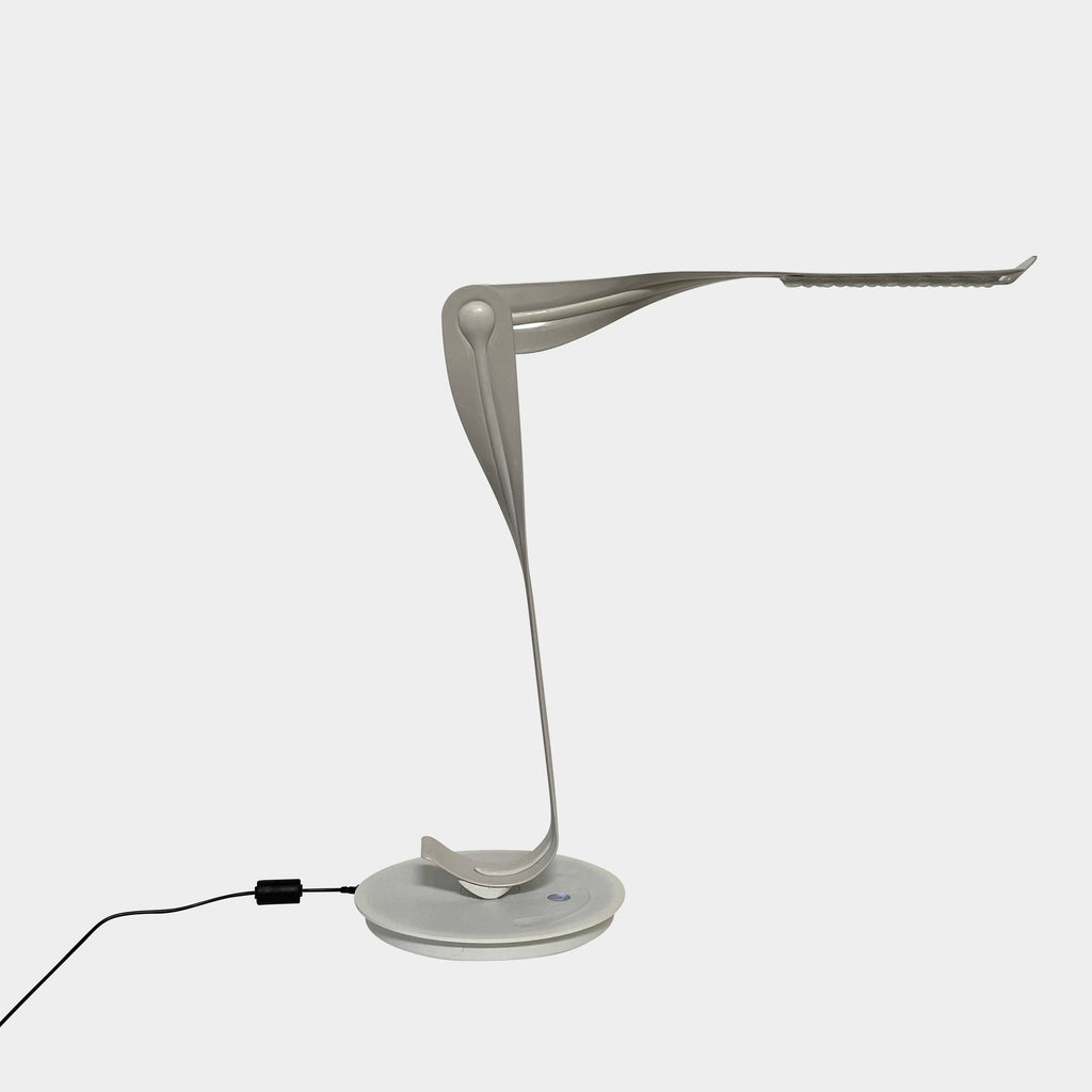 A sleek, modern Herman Miller Leaf Task Light with a curved design on a circular base, connected to a power cord.