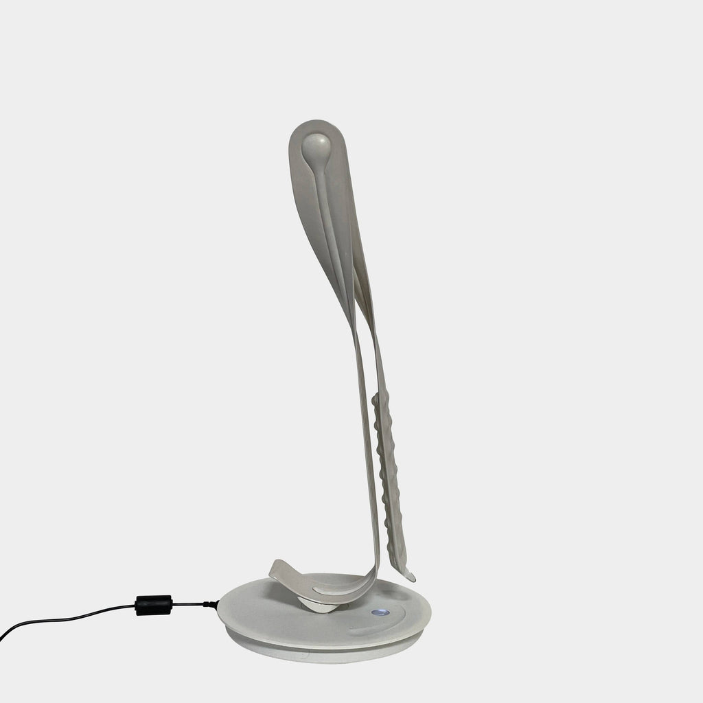 A sleek, modern Herman Miller Leaf Task Light with a curved design on a circular base, connected to a power cord.