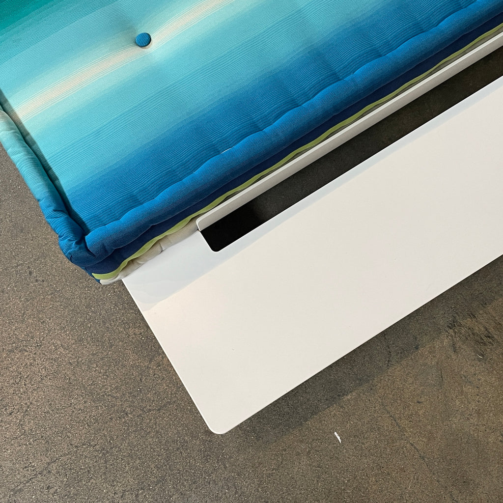 A modern, multicolored Roche Bobois Mah Jong Chaise Lounge from Roche Bobois with a gradient pattern in blue, green, and yellow shades, featuring a cushioned backrest and a matching pillow on a white base for perfect outdoor relaxation.