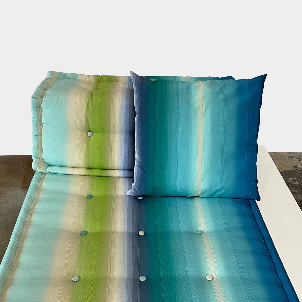 A modern, multicolored Roche Bobois Mah Jong Chaise Lounge from Roche Bobois with a gradient pattern in blue, green, and yellow shades, featuring a cushioned backrest and a matching pillow on a white base for perfect outdoor relaxation.