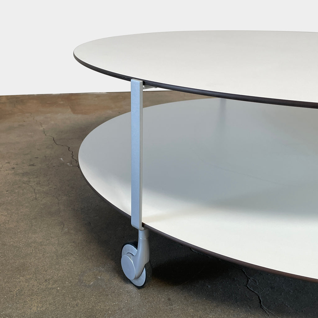 A Zanotta Giro Coffee Table, a round, white, two-tiered coffee table with a minimalist design, featuring a solid top and an open lower shelf for storage. The sleek steel frame adds durability, making it both stylish and functional.