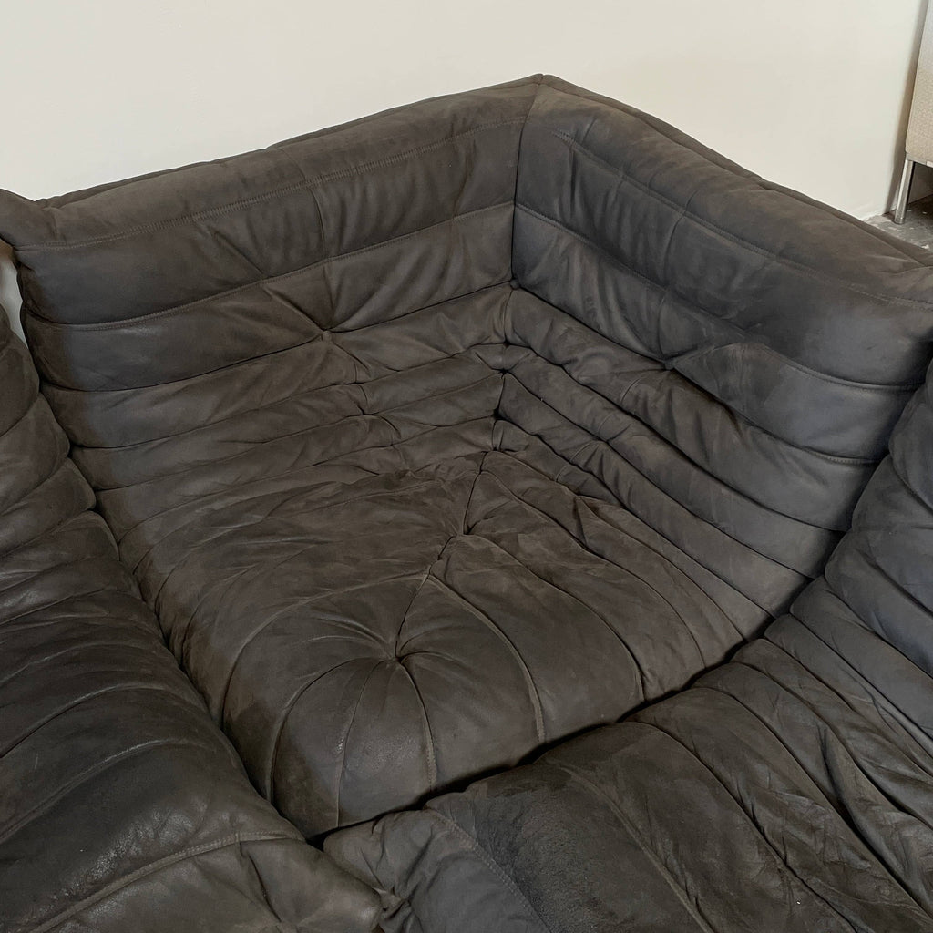 Ligne Roset Togo Three Piece Sectional, a black leather L-shaped sofa by Ligne Roset, features tufted cushions and a low backrest with polyether foam for enhanced comfort, beautifully displayed on a white background.