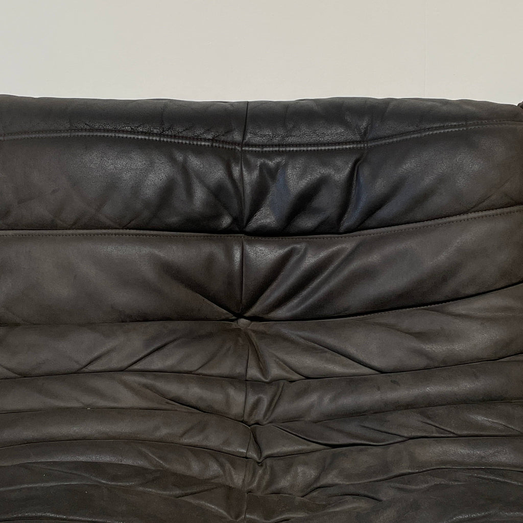 Ligne Roset Togo Three Piece Sectional, a black leather L-shaped sofa by Ligne Roset, features tufted cushions and a low backrest with polyether foam for enhanced comfort, beautifully displayed on a white background.