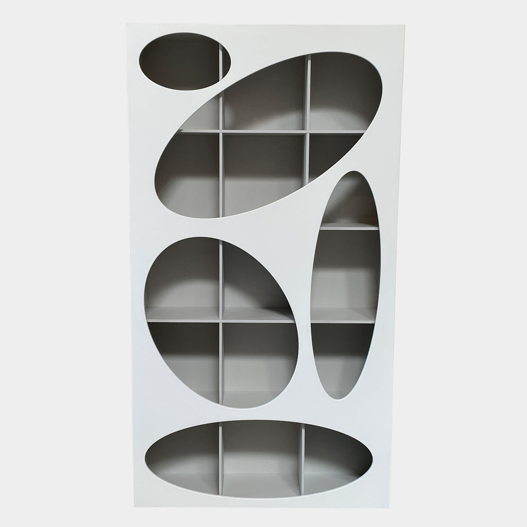 The Roche Bobois Denia Bookcase is a white bookshelf characterized by its abstract design, featuring multiple irregular oval cutouts, nine internal compartments, and integrated LED lighting, reminiscent of ROCHE BOBOIS styling.