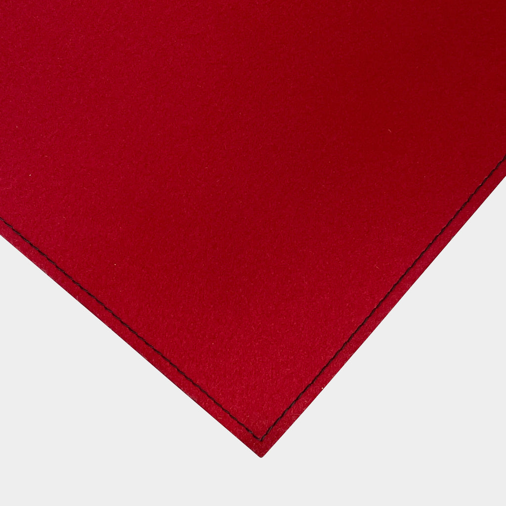 Close-up of the corner of a Large Felt Rug in a vibrant red color against a white background. The fabric showcases a clearly visible seam along its edge.