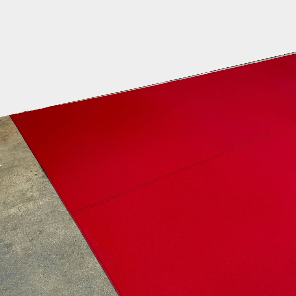 Close-up of the corner of a Large Felt Rug in a vibrant red color against a white background. The fabric showcases a clearly visible seam along its edge.