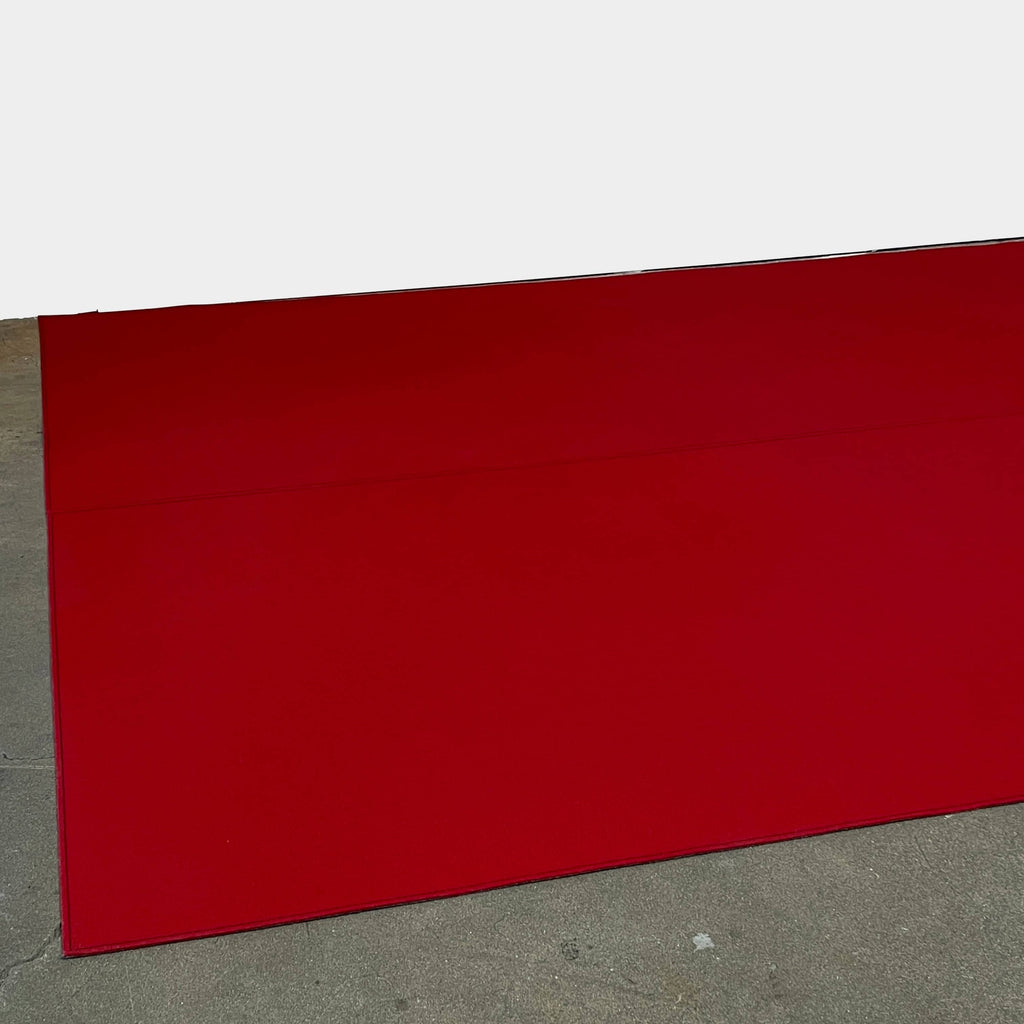 Close-up of the corner of a Large Felt Rug in a vibrant red color against a white background. The fabric showcases a clearly visible seam along its edge.