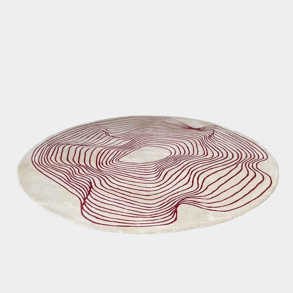 The Roche Bobois Volute Round Rug from Roche Bobois showcases a white surface decorated with red, wavy, parallel lines.