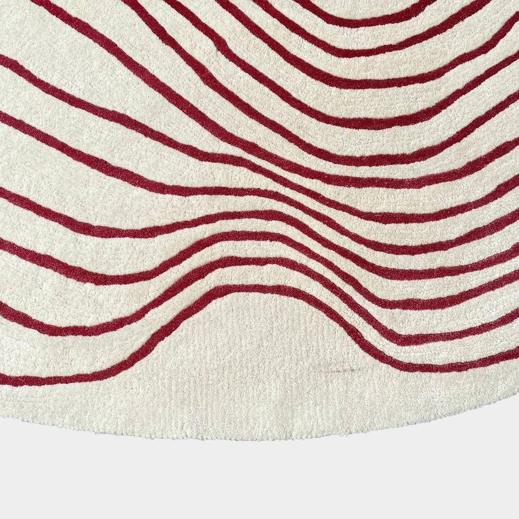 The Roche Bobois Volute Round Rug from Roche Bobois showcases a white surface decorated with red, wavy, parallel lines.