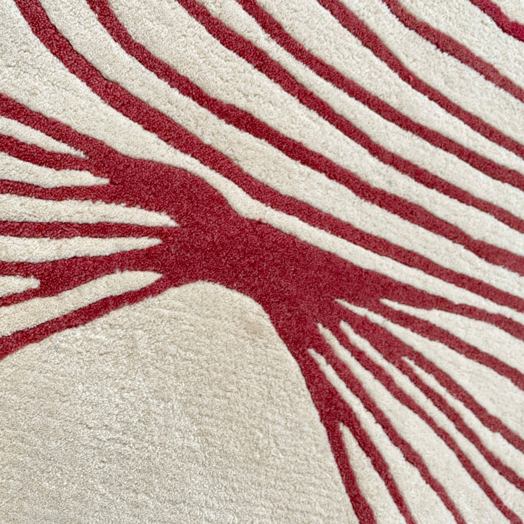 The Roche Bobois Volute Round Rug from Roche Bobois showcases a white surface decorated with red, wavy, parallel lines.