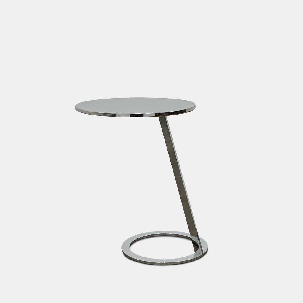 The Ligne Roset Good Morning Pedestal Side Table by Ligne Roset showcases a sleek, modern design with a round top and a distinctively angled chrome metal base on a circular foot.