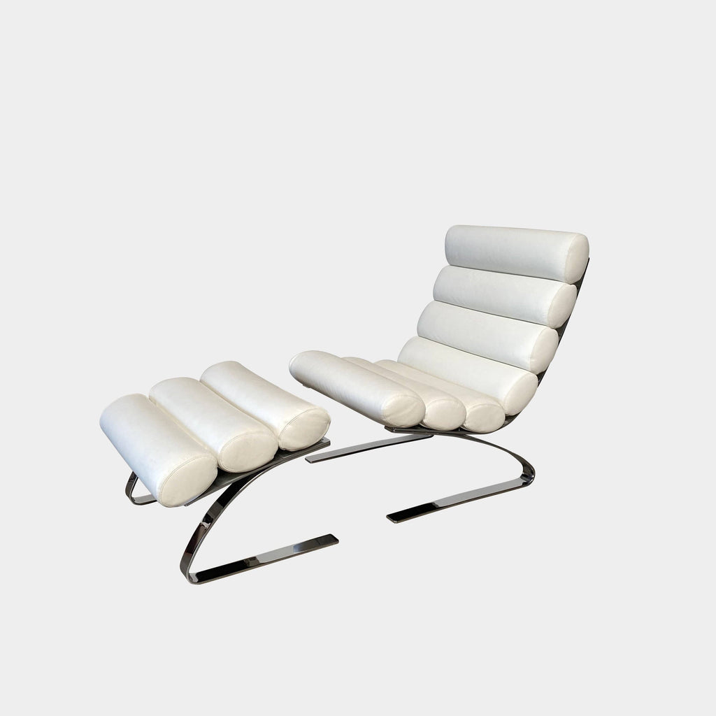 The COR Sinus Lounge Armchair and Ottoman by COR in polar white leather features a distinctive cylindrical cushion design and a chrome-plated frame, creating a striking presence on a concrete floor against a plain wall.