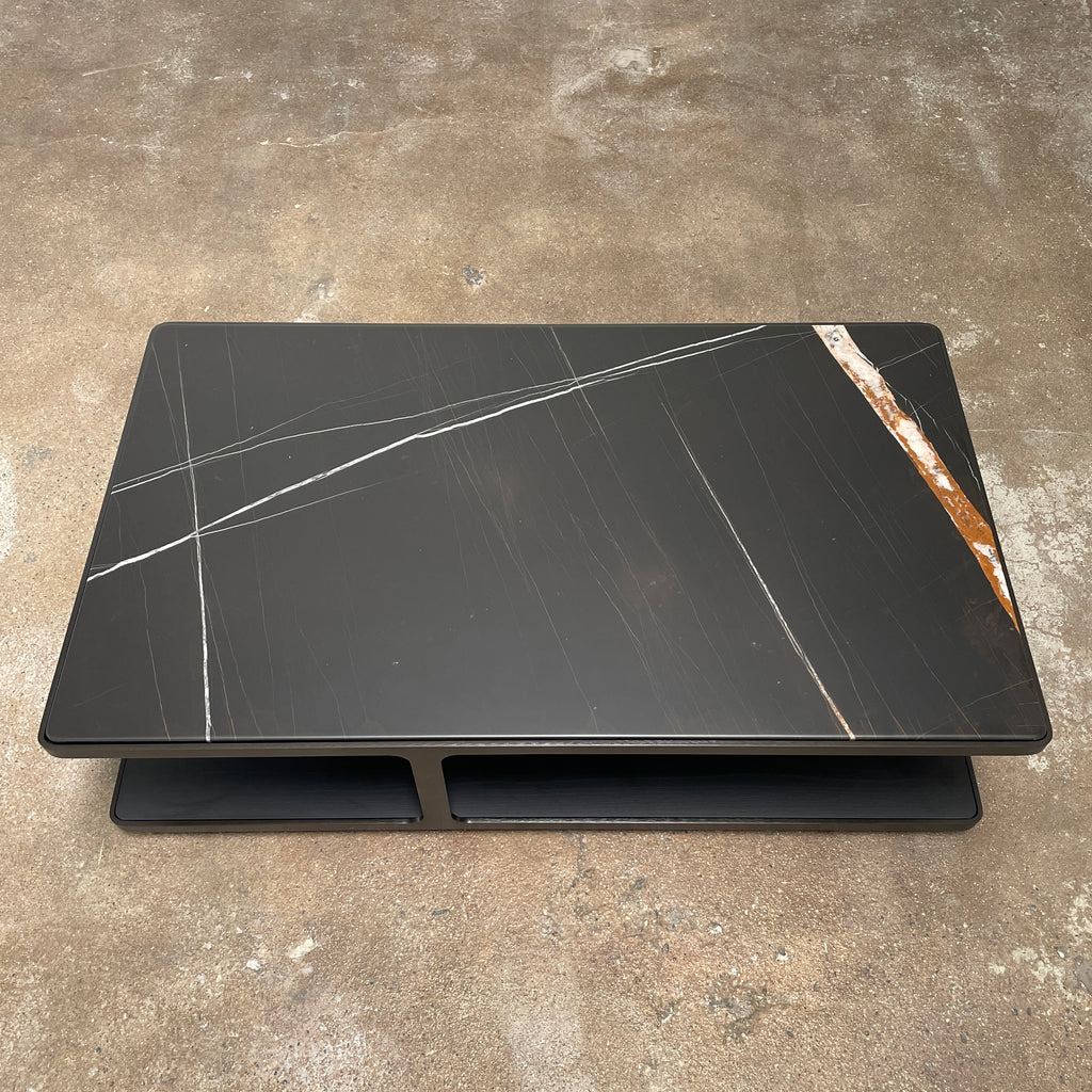 The Poliform Creek Marble Coffee Table by Poliform showcases a striking rectangular black marble surface adorned with intricate white and brown vein patterns, all elegantly supported by a brushed brown nickel frame that enhances its sophisticated design.