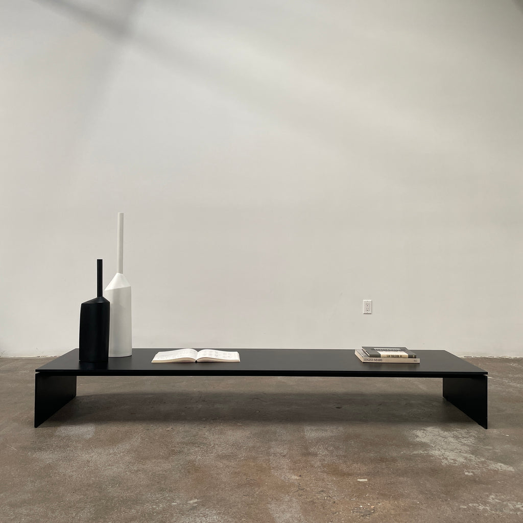 The Porro Modern Light Low Table by Piero Lissoni showcases a minimalist black design with a sleek metal structure and simple, rectangular legs, set against a plain background.